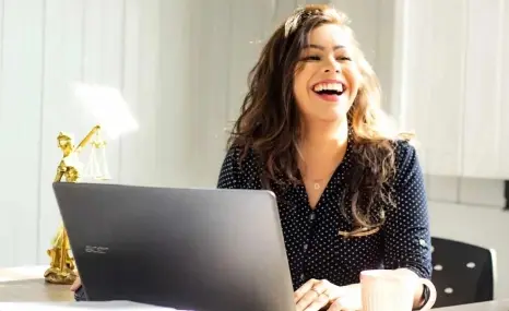Photographie d'une femme qui souris a son poste de travail
